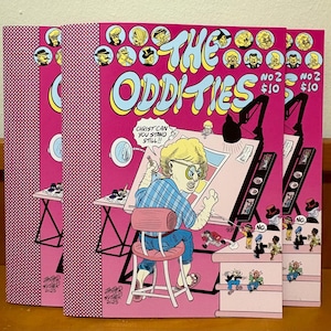 May include: Three comic books titled "The Oddities" with a pink cover featuring cartoon illustrations. The cover art includes the text "No 2 $10" and "Christ Can You Stand Still!!". The spine has a pink and white pattern and the text "Jasper Kthor 2025".