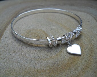 Pulsera de plata con anillos de plata y pequeño corazón de plata.