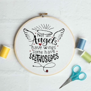Puede incluir: Un bastidor de bordado de punto de cruz con el texto "Not all Angels have wings, some have stethoscopes." El diseño incluye alas de ángel, corazones y un estetoscopio. La imagen también muestra carretes de hilo y unas tijeras azules.