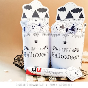 Può includere: Due contenitori cilindrici in carta bianca con disegni a linee nere di fantasmi, gatti e case infestate con il testo "HAPPY Halloween". Una striscia di carta orizzontale nella parte anteriore mostra il testo "du bist mein Lieblingsgespenst!".