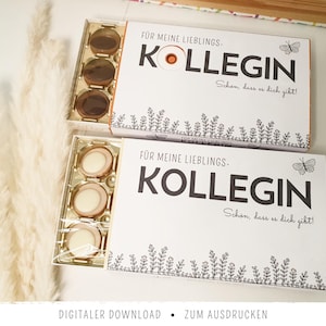 Peut inclure: Deux boîtes-cadeaux rectangulaires contenant des chocolats ronds, avec des couvercles blancs portant le texte noir FÜR MEINE LIEBLINGS-KOLLEGIN, SCHÖN, DASS ES DICH GIBT!, ornées d'une petite illustration de papillon et d'une bordure botanique.