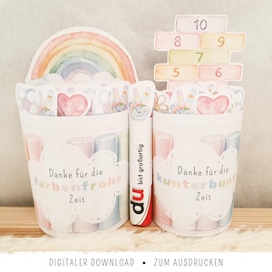 Puede incluir: Decoraciones de fiesta imprimibles estilo acuarela. Dos recipientes blancos con ilustraciones en colores pastel y el texto "Danke für die farbenfrohe Zeit" y "Danke für die kunterbunt Zeit". Un arcoíris y un bloque de números están en la parte superior. Un marcador con el texto "du bist großartig" está en el medio.