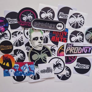 Pode incluir: Uma coleção de autocolantes variados com imagens da banda The Prodigy, incluindo logótipos circulares de formigas, etiquetas retangulares, um retrato de Keith Flint e ilustrações gráficas em preto, branco e cores vivas num fundo branco.