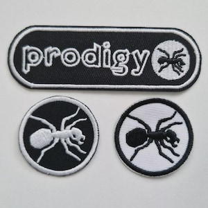 Könnte beinhalten: Drei gestickte Aufnäher. Der größte ist ein schwarzes Rechteck mit abgerundeten Ecken, dem Wort "prodigy" in Weiß und einem weißen Ameisenlogo. Zwei kleinere runde Aufnäher zeigen Ameisenmotive, eines weiß auf schwarz, das andere schwarz auf weiß.