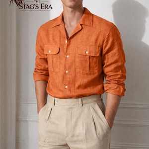 Puede incluir: Una camisa de lino naranja con dos bolsillos en el pecho y cuello de solapa se combina con pantalones plisados beige. La camisa tiene mangas largas y botones blancos. El logotipo de The Stag's Era está en la esquina superior izquierda.