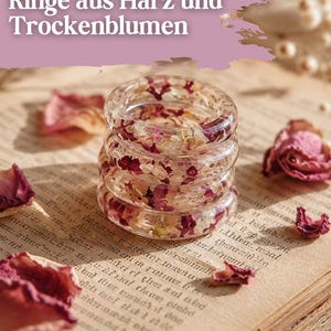 Könnte beinhalten: Ein Stapel aus drei Ringen aus klarem Harz mit eingebetteten getrockneten Blütenblättern in Rosa, Creme und Burgunderrot. Die Ringe sind kreisförmig mit einer glatten, polierten Oberfläche, die die natürliche Textur der botanischen Elemente zeigt.