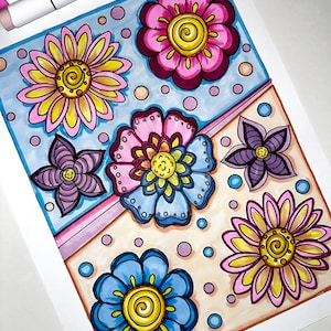 May include: A hand-drawn illustration on paper featuring a variety of colourful flowers including pink, yellow, blue, and purple blossoms. The design is divided by a diagonal pink line, with scattered small circles in blue, pink, and peach.
