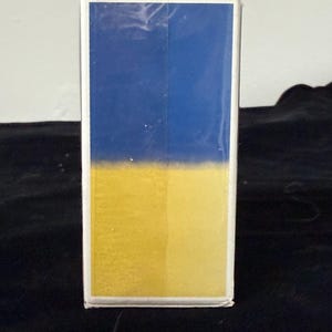 May include: A rectangular box with a blue top half and a yellow bottom half. The box has a white border and is set against a dark background.