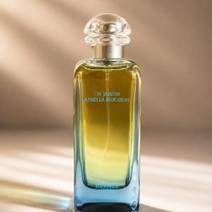 May include: A rectangular glass perfume bottle with a gradient color transition from deep blue at the base to a bright yellow-green at the top. The bottle features a clear rounded cap and the text UN JARDIN APRÈS LA MOUSSON and HERMES PARIS.