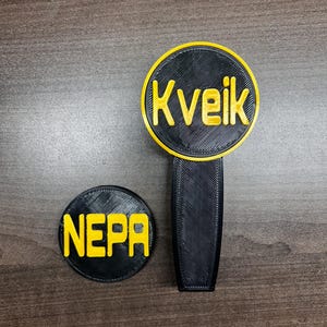 Pode incluir: Uma pega de torneira preta e amarela com a palavra "Kveik" em letras amarelas. Um emblema circular preto e amarelo a condizer com a palavra "NEPA" também está presente. Ambos os artigos são impressos em 3D.