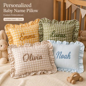 May include: Four personalized baby name pillows with gingham patterns and ruffled edges. The pillows are yellow, green, beige, and blue, each embroidered with a different name: Emma, Lucas, Olivia, and Noah. The pillows include inserts and covers.
