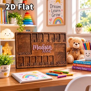 Könnte beinhalten: Ein rechteckiger Bilderrahmen aus Holz für Schuljahre mit Fächern, die von Preschool bis Senior beschriftet sind. In der Mitte steht der Name Madison Anne in rosa Schreibschrift. Der Rahmen hat ein dunkles Holzfinish mit Metallbeschlägen an den Ecken und bietet Platz für Fotos der einzelnen Klassenstufen.