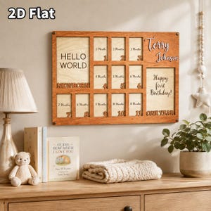 Könnte beinhalten: Ein rechteckiger Holz-Bilderrahmen mit heller Holzrückwand und dunklem Holzrahmen. Er enthält Fächer mit der Beschriftung 1 Month bis 11 Months sowie Bereiche für Hello World, Newborn, One Year, den Namen Terry Johnson und den Text Happy first Birthday.