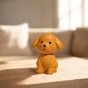 May include: A small, hand-carved wooden dog figurine with a golden-brown finish. The puppy has a textured, faceted surface, floppy ears, black painted eyes and nose, and soft pink blush marks on its cheeks, depicted in a seated position.