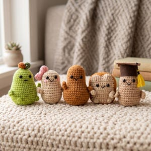 Op de afbeelding: Vijf handgemaakte gehaakte amigurumi-figuren. De figuren zijn in de vorm van een peer, een persoon met een strik, een pinda, een stuk brood en een afgestudeerde. De figuren zijn in groen, beige en bruin.