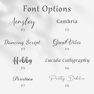 May include: An image displaying eight font options, including Ainsley, Cambria, Dancing Script, Great Vibes, Hobby, Lucida Calligraphy, Peristiwa, and Pretty Dahlia. Each font is accompanied by a code, such as F1 or F2, for easy reference.