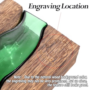 May include: A wooden block with an engraved design, next to a green glass object. The text "Engraving Location" is at the top. The note at the bottom says the engraving may not be very prominent due to the wood colour.