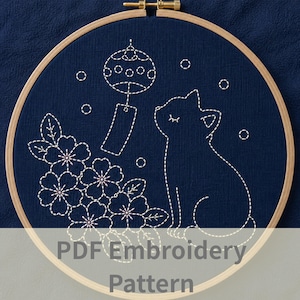 以下が含まれることがあります： 紺色の刺繍枠。白い糸で猫、桜、風鈴が刺繍されています。「PDF Embroidery Pattern」の文字が下部に表示されています。枠は木製です。