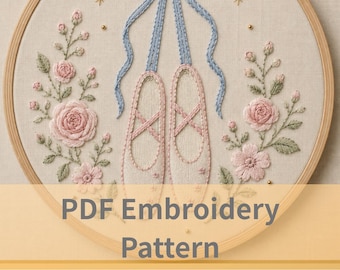May include: A circular wooden embroidery hoop containing a fabric panel with a hand-stitched design of light pink ballet slippers tied with a blue ribbon bow. The slippers are flanked by embroidered pink roses, green leaves, and small gold stars.