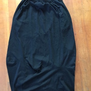 May include: A black skirt with an elastic waistband. The skirt is made of a soft, stretchy fabric and has a relaxed fit.