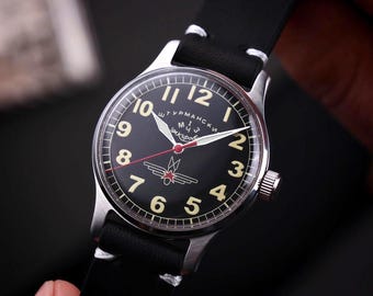 May include: A black wristwatch with a silver case and a black leather band. The watch face features white numerals, white hands, and a red star emblem. The watch has a classic, vintage aesthetic.