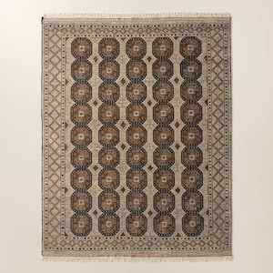 May include: Rectangular area rug with a geometric pattern in shades of brown, beige, and navy blue. The rug features a central design of repeating octagons and diamonds, framed by a detailed border with fringe on the short ends. The rug is suitable for living rooms and bedrooms.