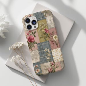 Może przedstawiać: Etui na telefon z patchworkowym wzorem z kwiatowymi wzorami w kolorze różowym, zielonym i niebieskim. Etui ma wygląd vintage z motywami róż i kwiatów. Etui na telefon spoczywa na białej powierzchni.