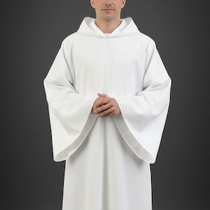 May include: A solid white liturgical alb featuring a structured hood, long wide sleeves, and a floor-length design. The garment is crafted from a smooth, opaque fabric with clean, minimalist lines and a simple, unadorned aesthetic throughout.