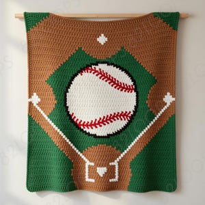 Pode incluir: Um cobertor de beisebol de crochê feito à mão. O cobertor apresenta um design de campo de beisebol com uma bola grande no centro. O campo é verde e marrom, com linhas brancas e uma bola com costuras vermelhas.
