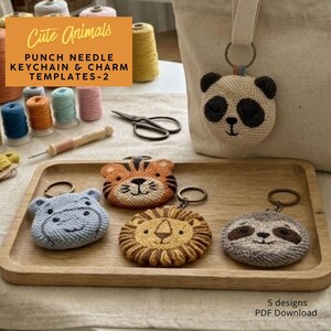 Puede incluir: Una colección de llaveros y plantillas de amuletos de aguja mágica con diseños de animales lindos. Los llaveros incluyen un panda, un tigre, un hipopótamo, un león y un perezoso. La imagen también muestra carretes de hilo, tijeras y el texto "Cute Animals".