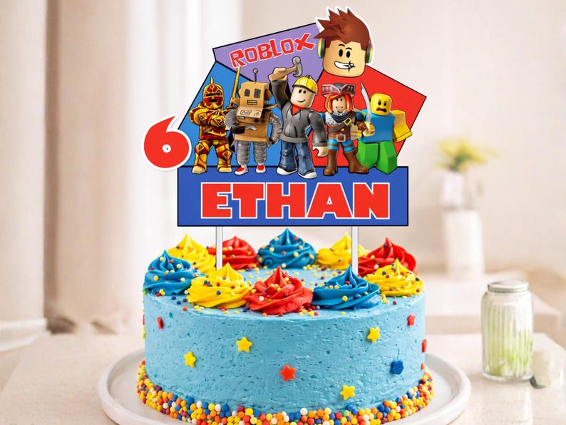 K&ouml;nnte beinhalten: Ein blau glasierter Kuchen, verziert mit bunten Zuckergusswirbeln und Streuseln. Ein Tortenaufsatz zeigt Roblox-Charaktere, die Zahl 6 und den Namen "ETHAN" in roten Buchstaben. Der Kuchen steht auf einem wei&szlig;en Teller.