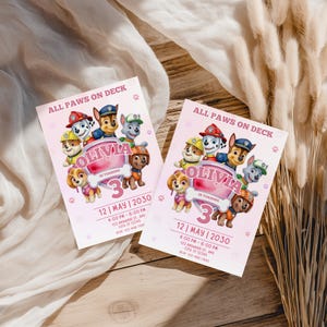May include: Two pink birthday party invitations with the text "ALL PAWS ON DECK" and "OLIVIA IS TURNING 3". The invitations feature cartoon images of the Paw Patrol characters and paw prints.