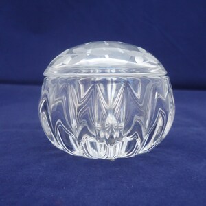 May include: A clear glass trinket box with a textured, faceted design. The lid has a frosted, etched pattern.
