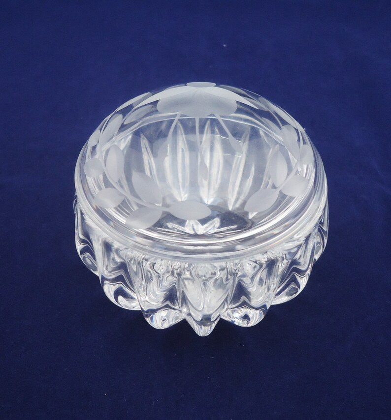 May include: A clear glass trinket box with a frosted lid. The lid has a floral design etched into it. The base of the box has a textured, wavy design.