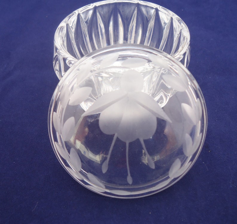 May include: A clear glass trinket box with a frosted etched design of a flower on the lid. The box has a fluted design on the sides.