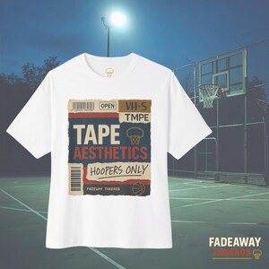 May include: White t-shirt with a graphic design featuring the words "TAPE AESTHETICS HOOPERS ONLY" in a vintage style. The design includes a basketball hoop and the text "FADEAWAY THREADS". The shirt is set against a basketball court background.