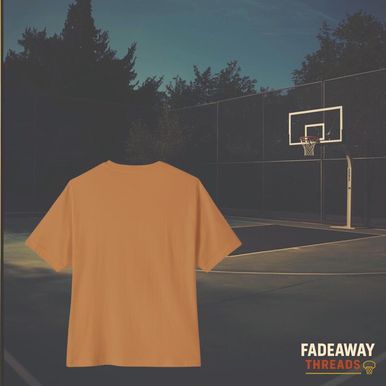 May include: A short-sleeved, orange t-shirt is the focal point of this image. The shirt is set against a backdrop of a basketball court and a hoop. The words "Fadeaway Threads" are printed in white and orange at the bottom right.