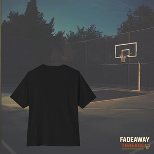 May include: A black t-shirt is centered in front of a basketball court. The court has a hoop and net. The text "FADEAWAY THREADS" is in the lower right corner. The background is a dusk scene with trees and a fence.