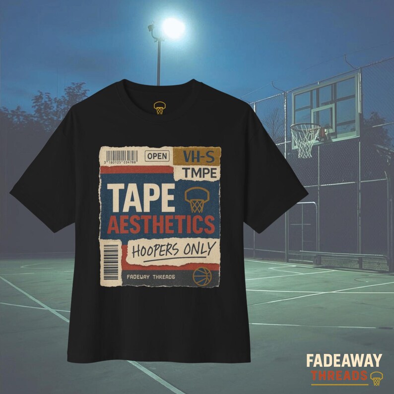 May include: Black t-shirt with a retro-style graphic. The graphic features the words "TAPE AESTHETICS HOOPERS ONLY" in a vintage design, along with a basketball hoop illustration. The shirt also has a small logo on the upper left and the brand name at the bottom.