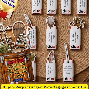May include: A collection of fishing-themed gift tags and a decorative box, with the words "Dad of the Year" on a gold emblem. The tags feature fishing-related illustrations and German text, perfect for Father's Day.