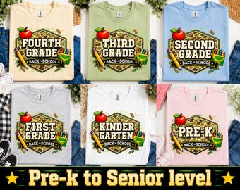 Puede incluir: Una colección de seis camisetas en varios colores, incluyendo crema, verde claro, azul claro, gris, blanco y rosa claro. Cada camiseta presenta un gráfico con una manzana roja, un lápiz amarillo, crayones y texto que indica el nivel escolar.