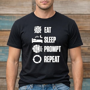 May include: Black t-shirt featuring white text and graphics. The design includes a fork and knife, a bed with a crescent moon, a brain with circuit board elements, and a circular arrow. The text reads: EAT, SLEEP, PROMPT, REPEAT.