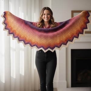 Peut inclure: Un châle fait à la main aux couleurs vives, avec un motif en chevrons. Le châle présente un dégradé de couleurs, notamment du violet, du rose, de l'orange et de la crème. Les bords ont un design festonné. Le châle est tenu ouvert, montrant sa taille et son design.