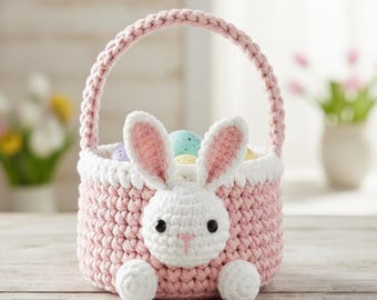 May include: A handmade pink crochet Easter basket with a white bunny face and ears. The basket has a handle and is filled with colorful Easter eggs. The bunny face has black eyes and a pink nose. The basket is sitting on a wooden surface.