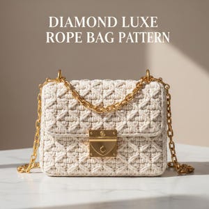 May include: Cream-colored rope bag with a diamond pattern and gold-tone chain strap. The bag features a gold clasp and the text "DIAMOND LUXE ROPE BAG PATTERN" at the top. The bag is on a white surface.