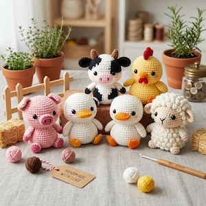 Puede incluir: Una colección de juguetes de animales de granja hechos a mano con ganchillo, que incluyen un cerdo, una vaca, un pollo, una oveja y patos. Los juguetes son de varios colores y están colocados sobre una mesa con ovillos de lana, un ganchillo y una etiqueta que dice "HANDMADE WITH LOVE".