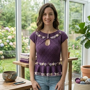 May include: A purple crochet top with a keyhole neckline and cap sleeves. The top is adorned with floral embellishments around the neckline and waist. The woman is wearing blue jeans.