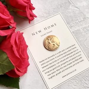 May include: A gold-colored lucky penny with the year 1903 inscribed on it. The penny is on a white card with the text "New Home Lucky Penny" and instructions on how to use the penny as a good luck charm for a new home.