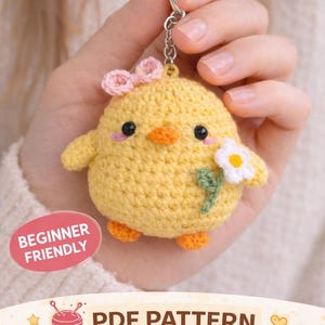 May include: A yellow crocheted chick keyring with a pink bow, orange beak and feet, and a white flower. The keyring is attached to a silver ring. The text "BEGINNER FRIENDLY" and "PDF PATTERN" are also visible.