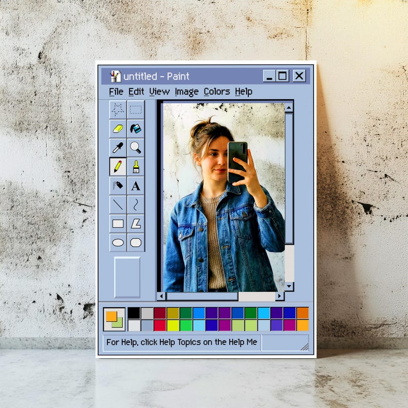 Może przedstawiać: Oprawione dzieło sztuki przedstawiające interfejs retro programu Windows Paint. Obraz w ramie przedstawia osobę robiącą selfie. Interfejs programu Paint zawiera opcje menu i paletę kolor&oacute;w na dole. Widoczny jest tekst "untitled - Paint".